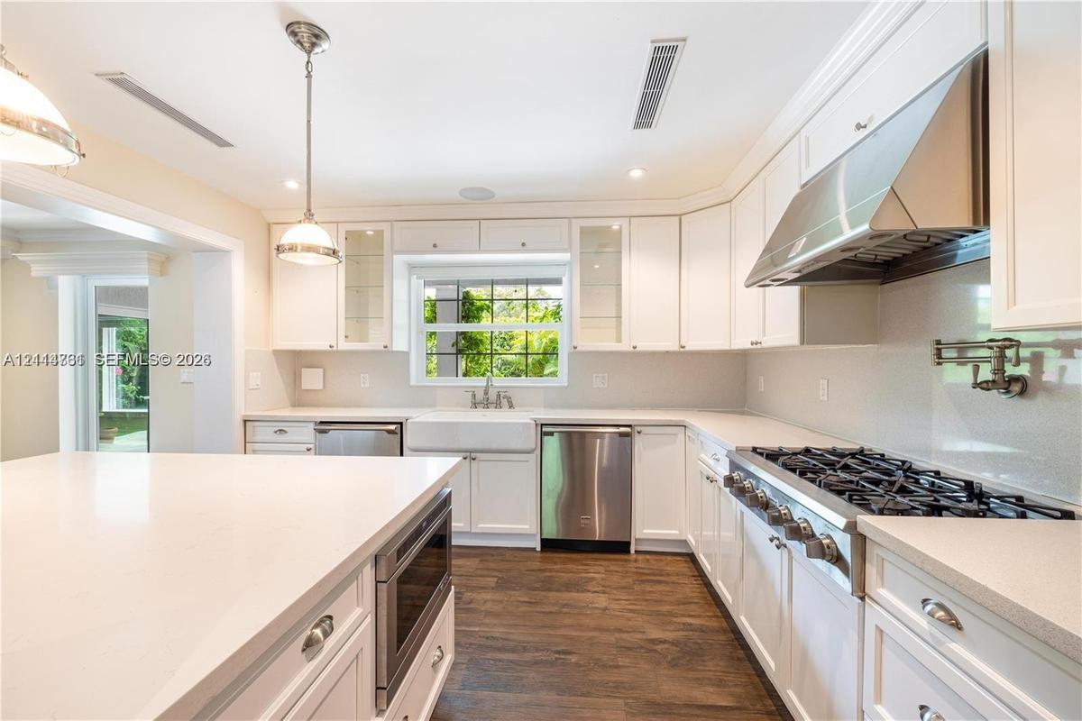 Kitchen featuring white cabinetry, quartz countertops, a farmhouse-style apron sink, professional-grade stainless steel range with matching hood, and 