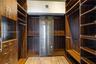 Custom walk-in closet featuring wood-finish cabinetry, built-in drawer units, adjustable shelving, integrated hanging rods, and glass-front cabinetry 