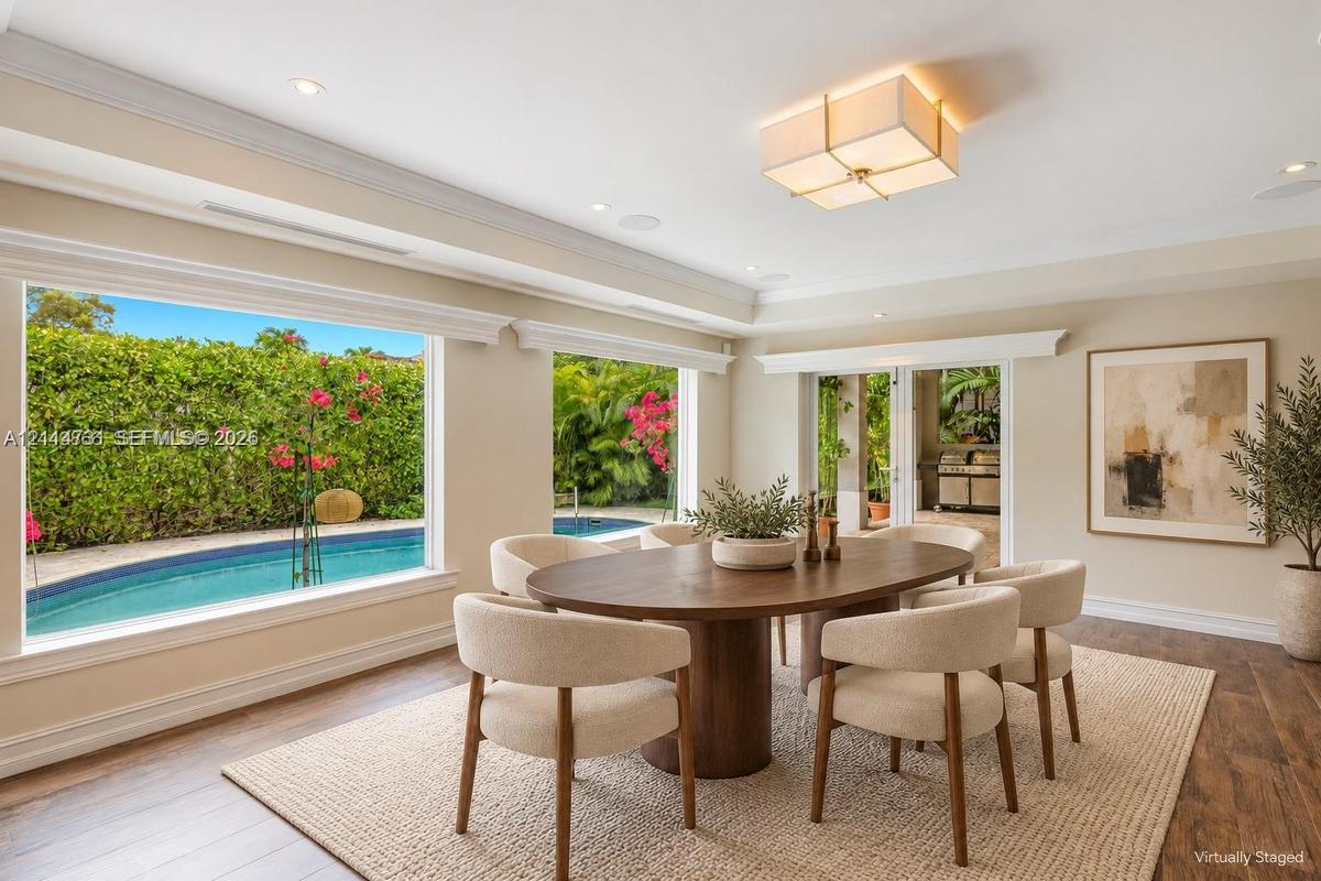 Living area featuring wood-finish flooring, crown molding, a box-style chandelier, expansive windows, and direct access to an outdoor swimming pool