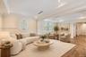 Tray ceilings with recessed lighting, oval accent window with plantation shutters, and wood-finish flooring