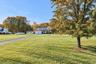 Two-story residence featuring a dual-bay garage, an asphalt driveway, and expansive lawn space