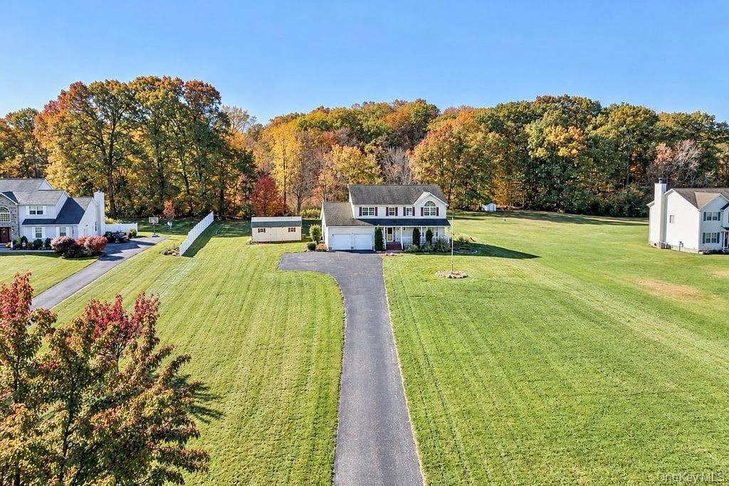 Two-story residence featuring a two-car attached garage, expansive lot, paved driveway, and detached storage shed