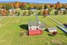Aerial perspective of a detached residence featuring a large exterior deck, detached storage shed, and expansive acreage