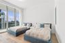 Floor-to-ceiling glass windows, wide-plank wood-finish flooring, and a private balcony with glass railing