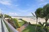 Outdoor terrace featuring glass paneled railings, wood-finish decking, tiered stairways, and private beach access