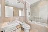 Full-height stone wall tiling, custom vanity with a stone countertop and undermount sink, frameless glass shower enclosure, and a large wall-mounted m