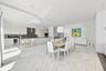 Open-concept kitchen and dining area featuring stone-finish flooring, high-gloss cabinetry, stainless steel range hood, built-in refrigerator, and dua