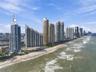 High-rise oceanfront residential tower featuring floor-to-ceiling glass paneling and direct coastal positioning