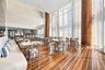 Double-height space featuring floor-to-ceiling glass, inlaid wood-finish flooring, decorative cylindrical columns with wood-toned cladding, and textur