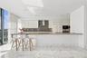 Gourmet kitchen featuring high-gloss cabinetry, stone-surface breakfast bar, built-in stainless steel appliances, recessed ceiling lighting, and polis