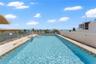 Rooftop swimming pool featuring a concrete deck, metal handrails, and a glass safety partition