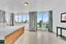 Large-format windows, sliding glass door with access to a balcony, light-toned stone-finish tile flooring, and a flush-mount ceiling light fixture
