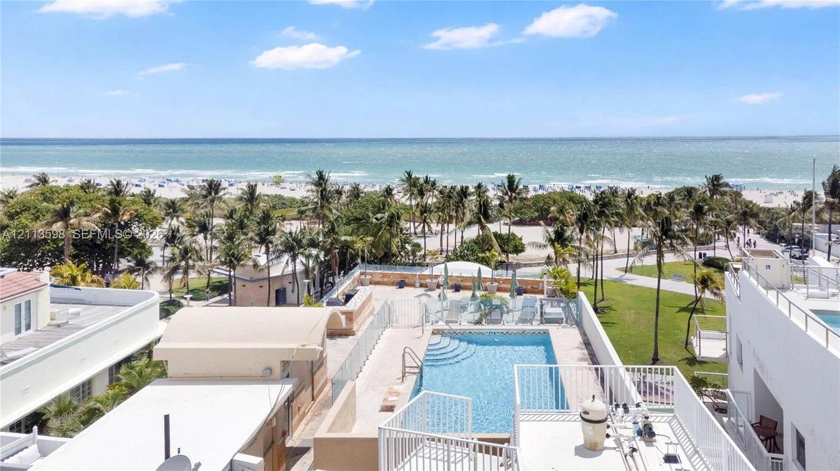 Rooftop terrace featuring an in-ground swimming pool, glass paneled railings, and expansive coastal scenery