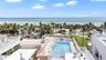 Rooftop terrace featuring an in-ground swimming pool, glass paneled railings, and expansive coastal scenery