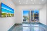 Floor-to-ceiling window featuring city skyline backdrop, polished blue-toned stone flooring, and recessed ceiling lighting