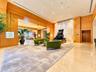 Expansive lobby featuring natural wood-paneled walls, polished stone flooring, recessed lighting, and a prominent stone-tiled accent wall