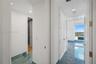 Hallway featuring polished blue-toned stone flooring, recessed ceiling lighting, and full-height interior doors