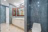 Bathroom featuring floor-to-ceiling blue stone wall tiling, double vanity with white cabinetry, light-toned stone countertop, recessed lighting, and w