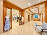 Polished stone flooring, custom wood-trim architectural detailing, recessed tray ceilings, and glass-paneled sliding entry doors