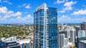 High-rise residential tower featuring a glass-curtain facade, recessed private balconies, and reinforced concrete structural elements