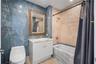Bathroom featuring blue-toned stone wall tiling, a white vanity with a stone countertop, a soaking tub with an integrated shower head, and a framed wa