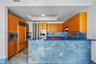 Kitchen featuring wood-veneer cabinetry, expansive blue stone-slab breakfast bar, integrated stainless steel appliances, built-in wall oven, and coord