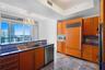 Kitchen featuring wood cabinetry, high-gloss stone countertops, stainless steel appliances, polished stone flooring, and expansive floor-to-ceiling wi