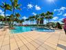 Large swimming pool with integrated circular spa, expansive tiled deck, and mature palm tree landscaping