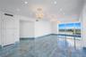 Polished stone flooring with blue-toned veining, three tiered crystal chandeliers with ceiling medallions, recessed lighting, and floor-to-ceiling win