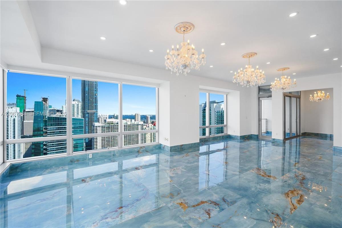 Polished stone flooring with blue veining, expansive floor-to-ceiling windows, recessed lighting, and multiple crystal chandeliers