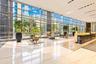 Expansive lobby featuring floor-to-ceiling curtain wall windows, polished stone flooring, recessed lighting, and a built-in reception desk with stone 