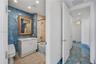 Bathroom featuring blue stone wall cladding, beige stone flooring, a vanity with a light-colored countertop, recessed lighting, and a bathtub with sto