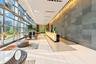 Grand lobby featuring floor-to-ceiling windows, large-format polished tile flooring, a prominent stone-tiled feature wall, recessed cove lighting, and