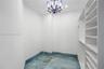 Walk-in storage space featuring built-in white shelving, recessed lighting, a decorative chandelier, and large-format polished stone flooring