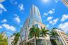 High-rise glass facade featuring modern architectural design, stone cladding, and mature palm tree landscaping