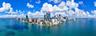 Panoramic aerial perspective of a high-rise urban skyline situated on a coastal peninsula with expansive surrounding waterfront