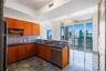 Kitchen featuring wood-finish cabinetry, solid surface countertops, stainless steel appliances, stone flooring, and expansive glass sliding doors