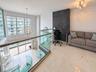 Mezzanine level featuring oversized windows, stone-finish flooring, a glass and metal railing, and a dark textured stone accent wall