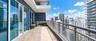 Expansive private balcony featuring floor-to-ceiling glass doors, neutral tile flooring, and a metal mesh railing
