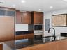 Kitchen featuring wood cabinetry, integrated panel-front refrigerator, dark solid-surface countertops, stainless steel wall oven and microwave, and a 