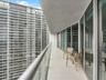 Balcony featuring oversized tile flooring, glass panel railing, and full-height sliding glass doors