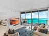 Floor-to-ceiling glass sliding doors, private balcony with metal railing, and light-toned tile flooring