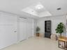 Interior space featuring a recessed tray ceiling, neutral tile flooring, and multiple closet enclosures with flush-panel doors