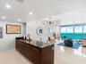 Kitchen featuring a dark-toned island with integrated sink, matte black faucet, and polished stone-finish countertops, complemented by recessed lighti