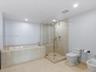 Bathroom featuring stone-tile flooring and surround, a deep soaking tub, and a frameless glass-enclosed shower with a built-in bench