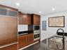 Kitchen featuring dark wood-finish cabinetry, built-in stainless steel double wall ovens, panel-ready refrigerator, polished stone countertops, and a 
