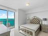 Floor-to-ceiling windows featuring expansive coastal and urban water panoramas, complemented by polished tile flooring and a flush-mount overhead ligh