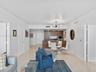 Open floor plan featuring light-toned tile flooring, recessed ceiling lighting, contemporary multi-arm chandelier, and kitchen cabinetry with integrat