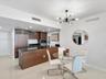 Kitchen featuring wood-finish cabinetry, black stone countertops, built-in refrigerator, matte black faucet, and modern multi-arm chandelier