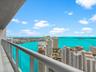 Balcony featuring a sleek metal railing and white tile flooring, offering expansive water and skyline scenery